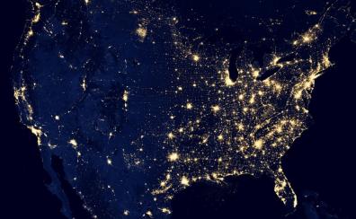 A satellite image of the United States at night, with the major cities and metro areas lit up.