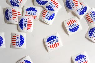 Scattered red white and blue "I voted" stickers across a white background