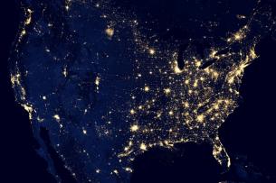 A satellite image of the United States at night, with the major cities and metro areas lit up.